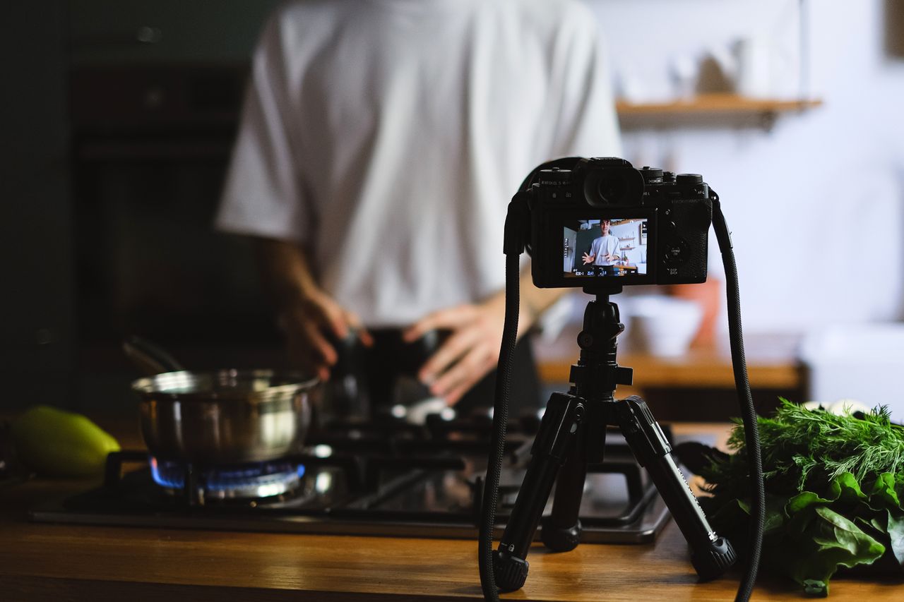 Un chef filme une démonstration culinaire dans une cuisine contemporaine avec des ingrédients frais.